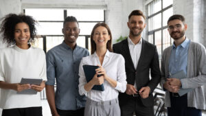 Corporate portrait successful smiling diverse employees team standing in office